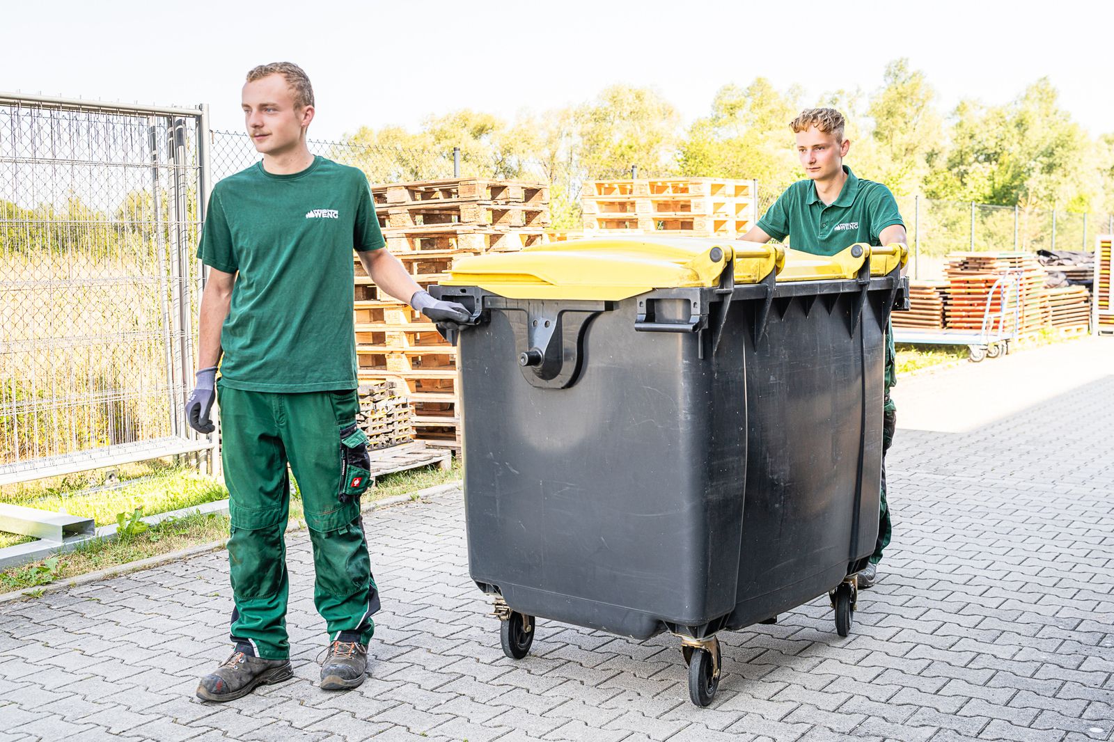 Zwei Mitarbeiter der WENG GmbH beim Mülltonnenservice auf dem Betriebsgelände