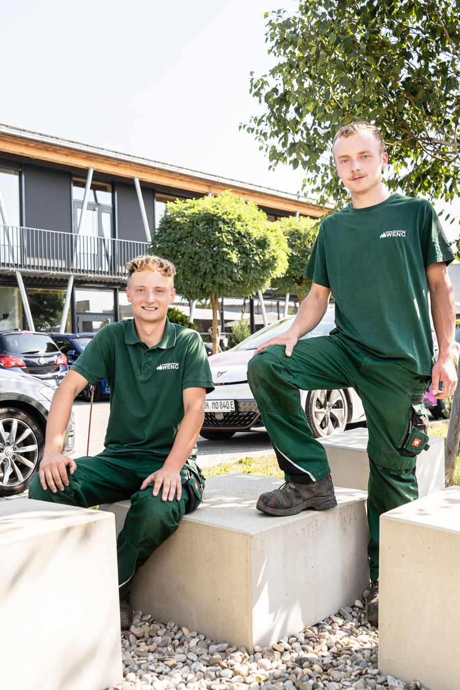 Zwei Mitarbeiter der WENG GmbH in grüner Arbeitskleidung vor dem Firmengebäude